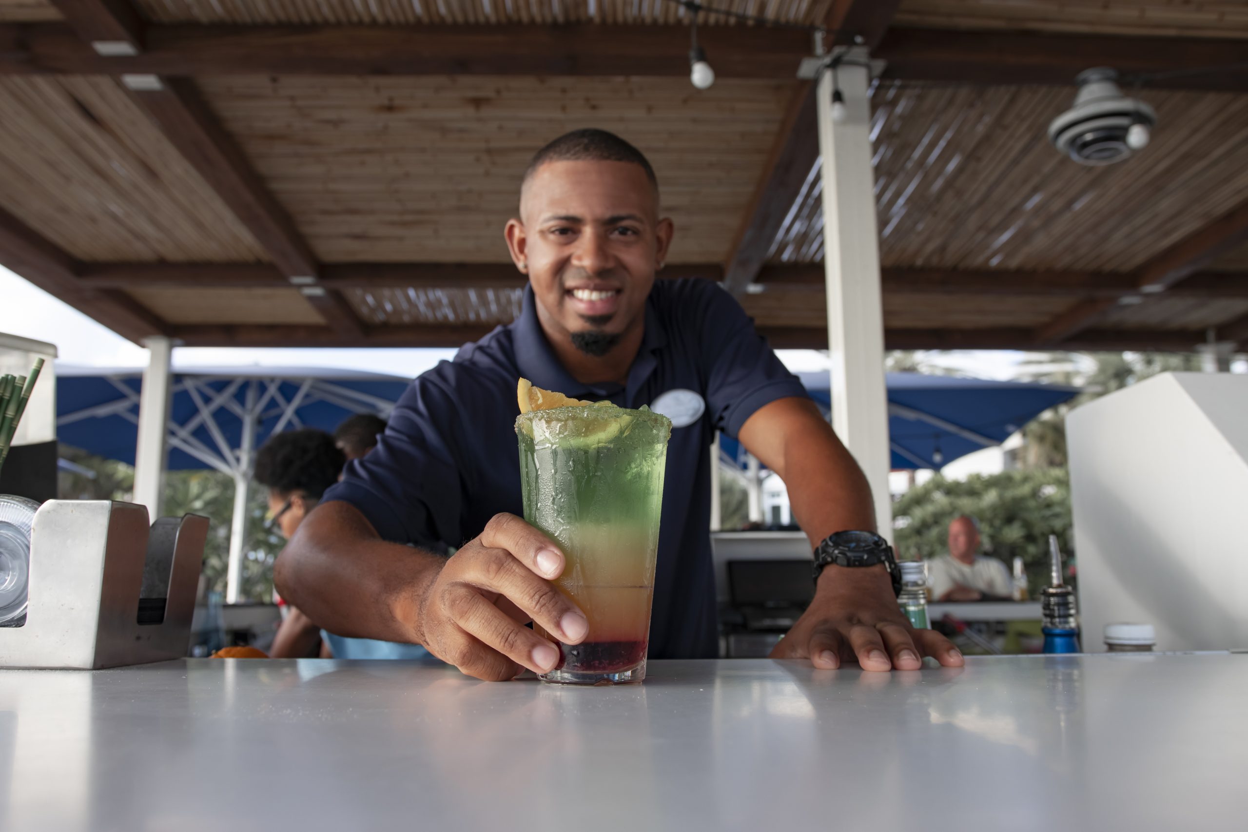 A young man standing behind a bar puts a drink on the counter